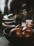 Onion Powder - Warm still life of onions in a wooden bowl on a rustic kitchen table.