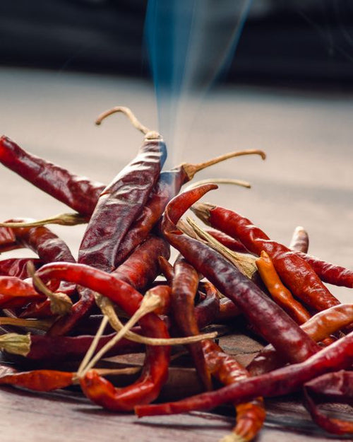 Arbol - Close-up of red chili peppers emitting smoke, highlighting the spicy essence.