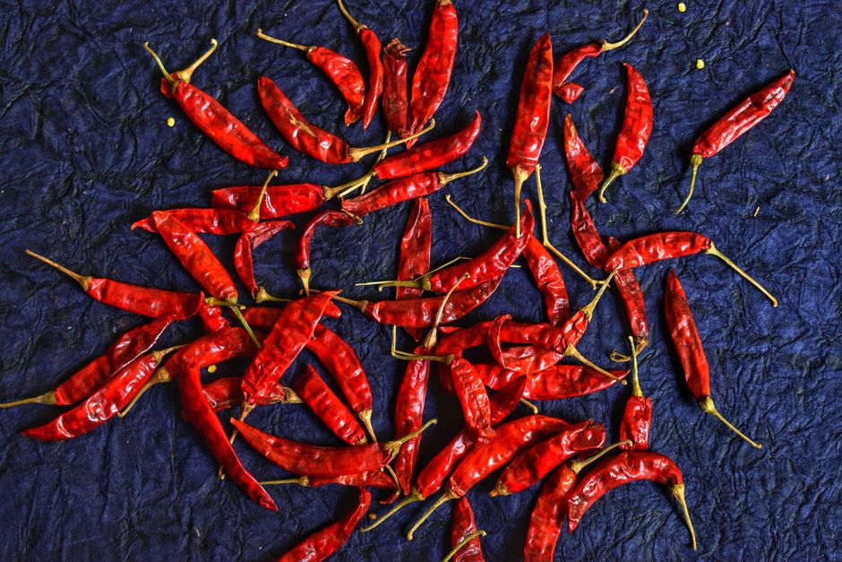 Yunnan - A collection of vibrant red chili peppers scattered on a textured blue background, highlighting their bold col