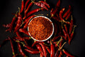 Chili Powder - Red chili powder and whole chilies on dark background, showcasing spice and flavor.