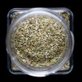 Marjoram - Herbs stored in a clear jar showcasing dried marjoram leaves from above.