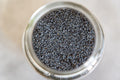Poppy Seeds - A detailed close-up of poppy seeds in a glass jar, highlighting texture and color.