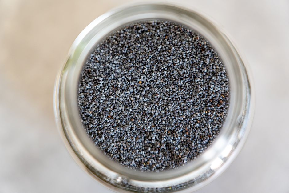 Poppy Seeds - A detailed close-up of poppy seeds in a glass jar, highlighting texture and color.