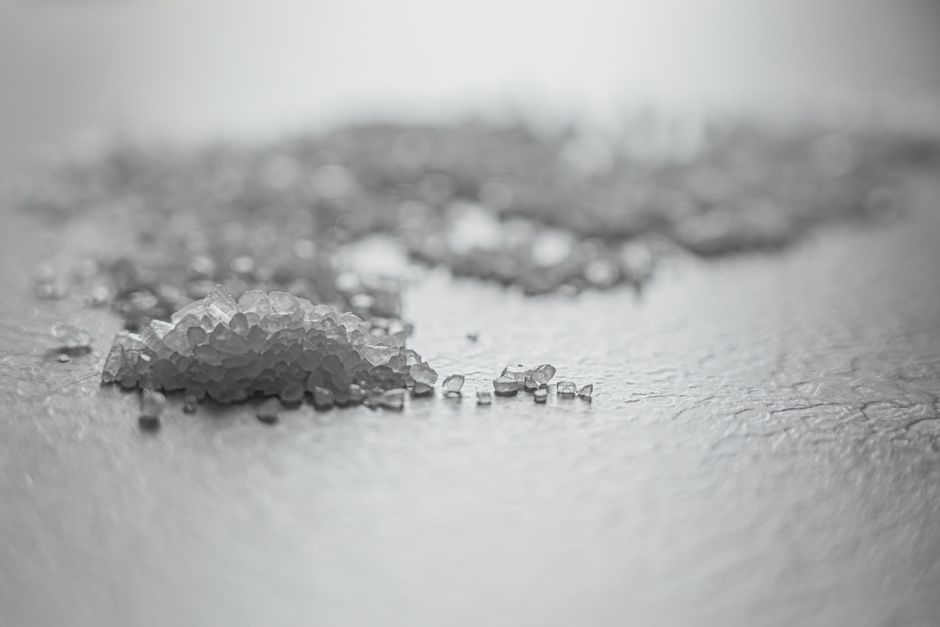Coarse Salt - Detailed shot of coarse rock salt scattered on a textured surface.