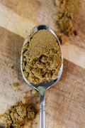 Cumin, Ground - A detailed close-up of ground cumin on a spoon, showcasing its texture.
