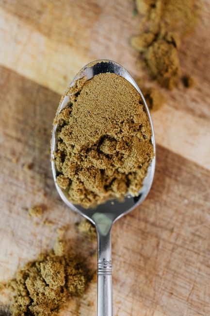 Cumin, Ground - A detailed close-up of ground cumin on a spoon, showcasing its texture.