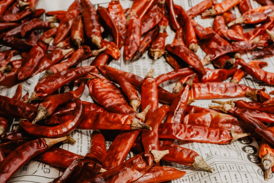 Paprika Pods - A vibrant display of dried red chili peppers spread out on a newspaper surface.