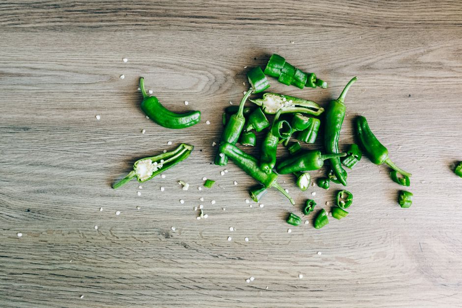 Jalapeno, Diced - Sliced green chili peppers with seeds on a wooden surface, highlighting freshness and texture.