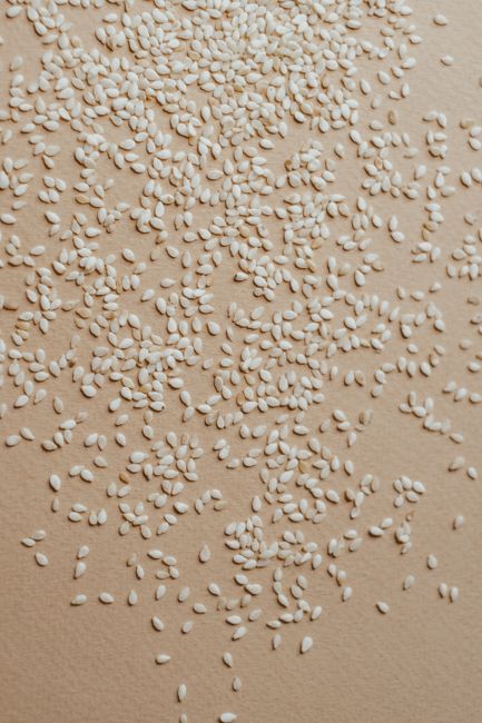 Sesame Seeds - A close-up view of organic raw sesame seeds scattered on a surface, ideal for nutrition concepts.