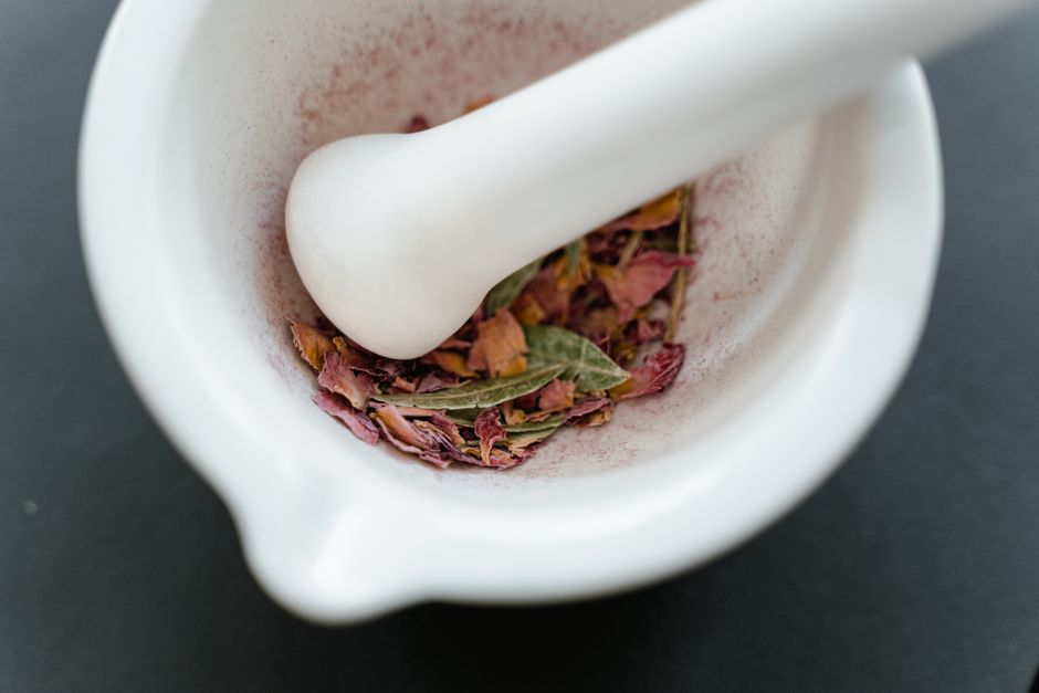 Safflower - A close-up view of dried herbal petals in a white mortar and pestle, creating a fragrant and aromatic setting.