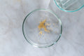 Mustard Powder / Flour - Top view of mustard seeds in a clear petri dish on a marble surface.